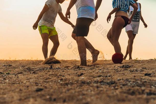 多种文化的朋友演奏足球同时向指已提到的人沙的海滩