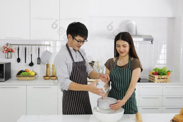 男人和女人帮助烹饪术意大利薄饼采用白色的厨房