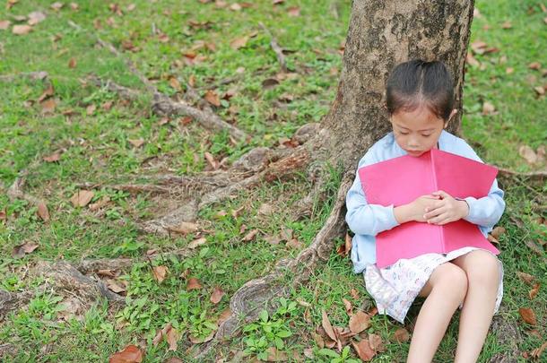 小的小孩女孩睡眠和书倾斜反对在下面树超铀元素处理工厂