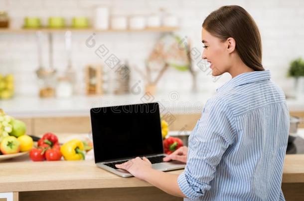 女人搜索的烹饪法在线的向便携式电脑和空白的屏幕