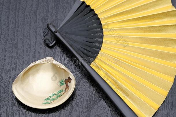 日本人金色的可折叠的扇子和海中软体动物的壳