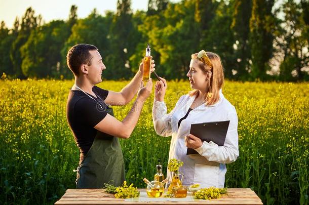 农学家女人和农场主检查油菜籽油和开花