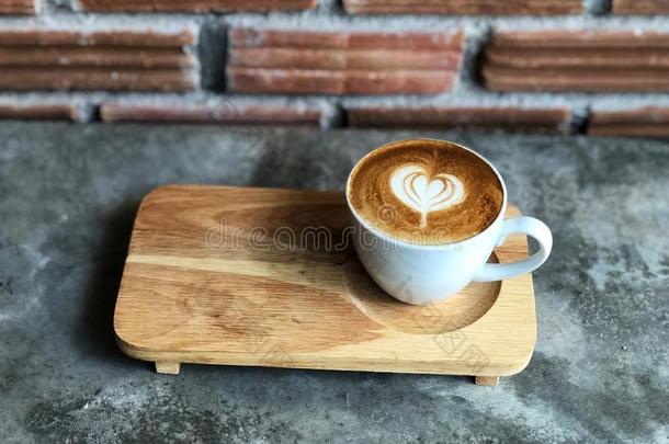 心爱短笛拿铁咖啡艺术采用白色的杯子向木制的盘子和cement水泥