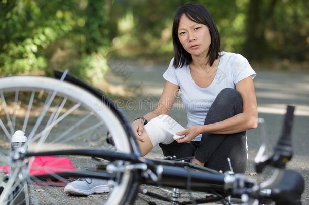 女人应用绷带向膝后的落下从自行车