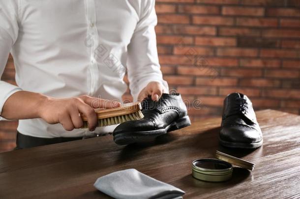 男人清洁皮鞋在木制的表在室内