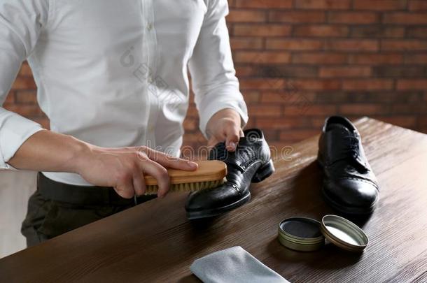男人清洁皮鞋在木制的表在室内