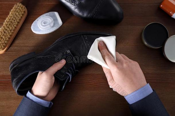 男人清洁皮鞋在木制的表