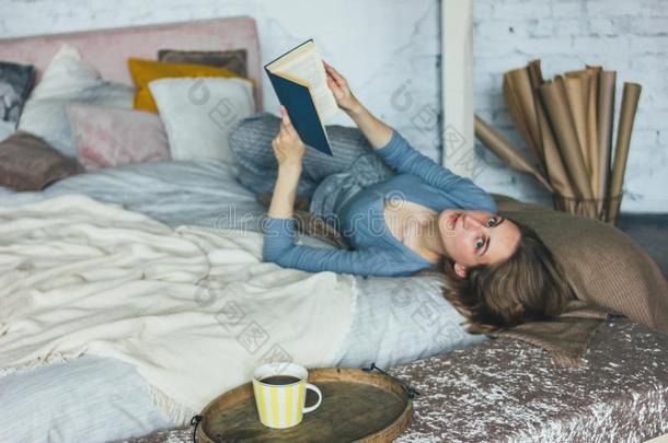 年幼的女人阅读书向床采用阁<strong>楼房</strong>间,慢的生活