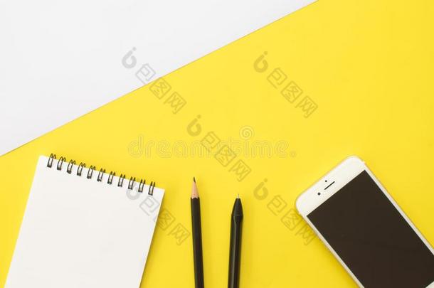 书,铅笔,笔,智能手机和眼睛眼镜向黄色的后台
