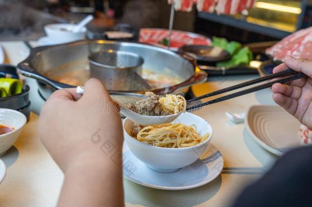 女人手使用筷子和勺在期间吃焖罐菜肴