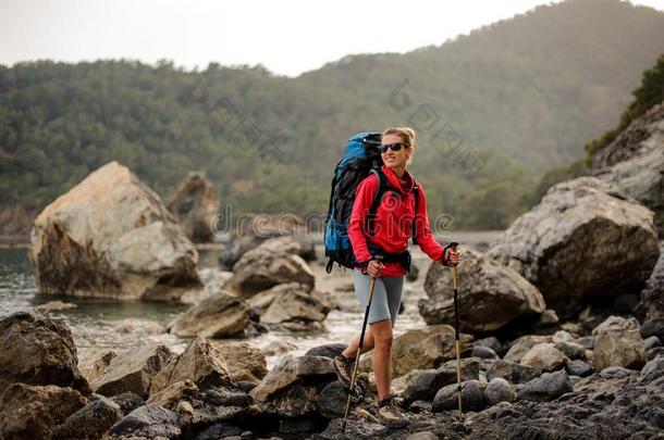 女人和徒步旅行设备艰苦跋涉通过多岩石的海岸