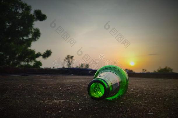 绿色的玻璃瓶子关于啤酒在日落天.空的啤酒瓶子.