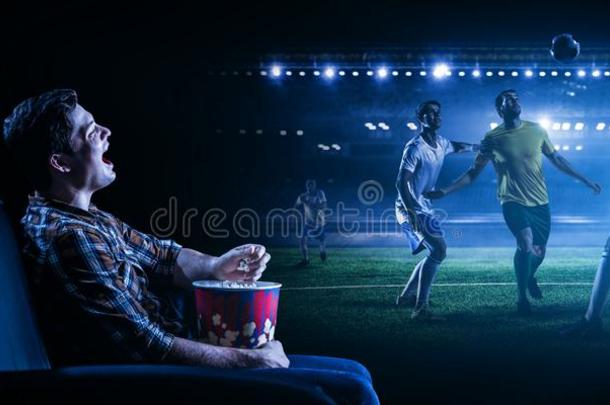 年幼的男人观察足球向大的屏幕