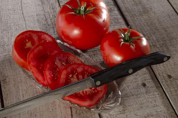 刨切的番茄和厨房刀向木材木板