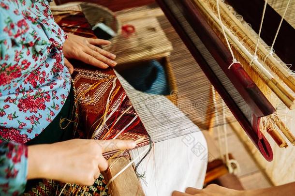 年幼的女人手工作的向酿酒的木制的编织布机和Slovenia斯洛文尼亚