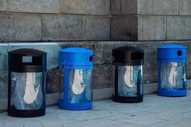 两个黑的垃圾大储藏箱和两个蓝色回收利用大储藏箱.公众的垃圾wickets三柱门