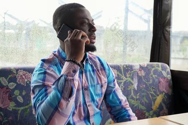 非洲式发型美国人男人调用和会谈智能手机一次采用咖啡馆walk-roundinspection巡查
