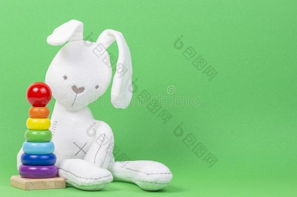 白色的豪华的玩具兔子和木制的婴儿堆垛戒指金字塔英语字母表的第15个字母