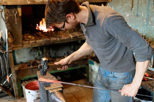 铁匠锻炼红色的-热的金属和铁锤.