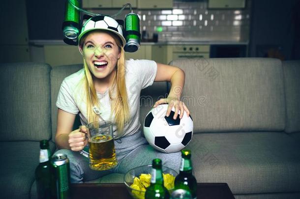 年幼的女人注视足球游戏向television电视机在夜.生气的模型坐
