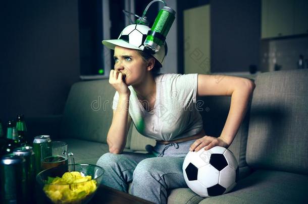 年幼的女人注视足球游戏向television电视机在夜.生气的打翻方式
