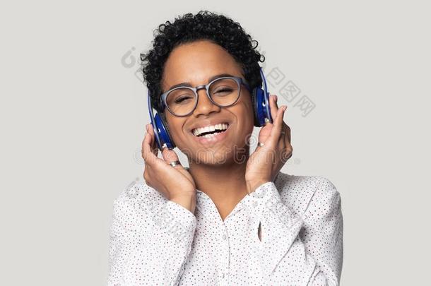 微笑的黑的女孩采用蓝牙耳机享有音乐