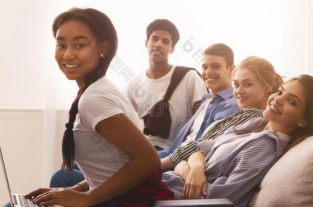 多种族的青少年学生静止的和书和便携式电脑向沙发
