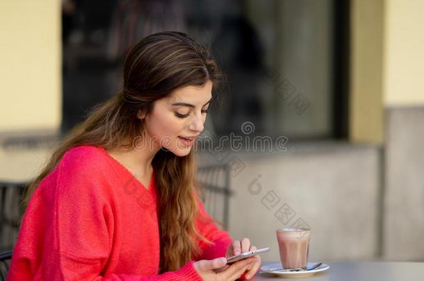 有魅力的年幼的女人使用聪明的可移动的电话计算机应用程序采用一咖啡豆