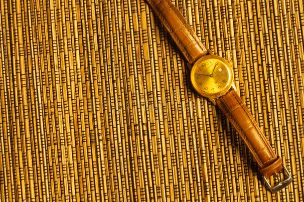 酿酒的金色的手表和皮用带捆扎向指已提到的人竹子后面