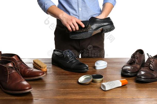 男人清洁皮鞋在木制的表反对白色的后台