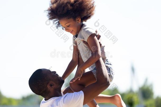 幸福的非洲的爸爸举起女儿在上面所有乐趣同时太棒了