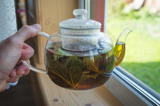 从透明的玻璃茶壶涌出黑的茶水采用玻璃马克杯,燃烧