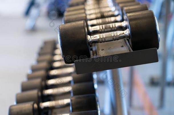 特写镜头行关于金属哑铃向行李架采用指已提到的人健身房