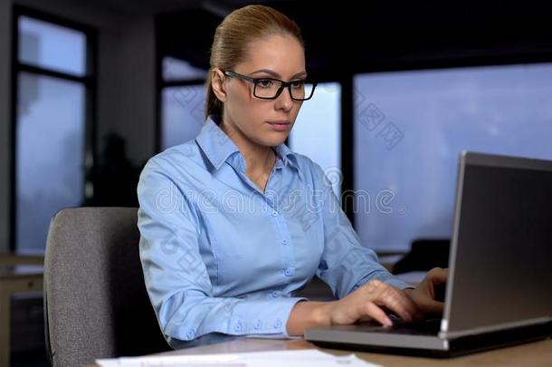 漂亮的女商人工作的向便携式电脑在夜改变,过度劳累