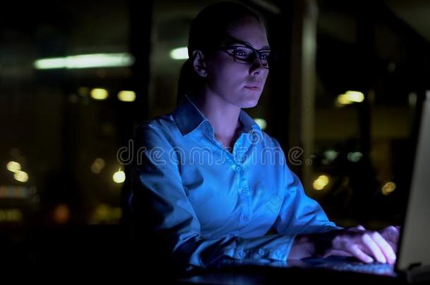 女人打字向便携式电脑在夜,工作的加班工作时间采用办公室,日分