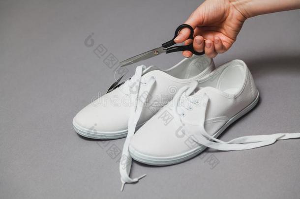 剪刀手切标签从落下新的白色的旅游鞋