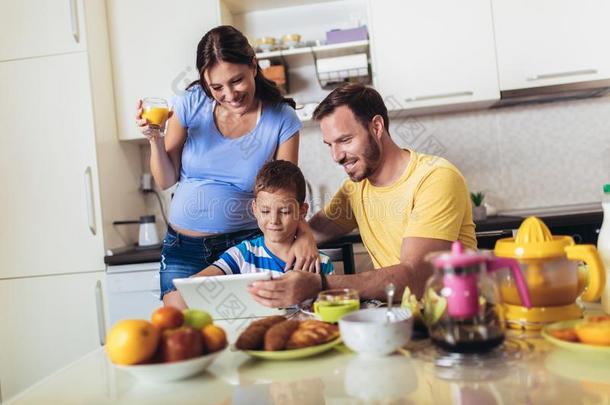 怀孕的女人和她家庭吃早餐采用指已提到的人厨房