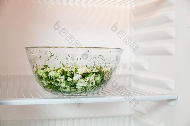 玻璃碗和蔬菜沙拉向架子关于冰箱