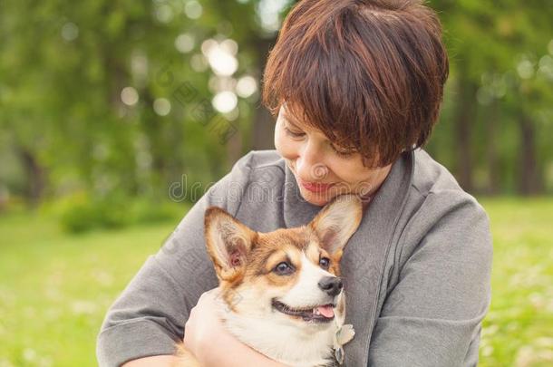 女人拥抱威尔士矮脚狗小狗狗,在户外肖像