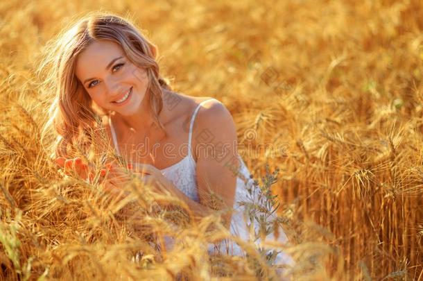 美丽的年幼的女人采用小麦田在日落户外的