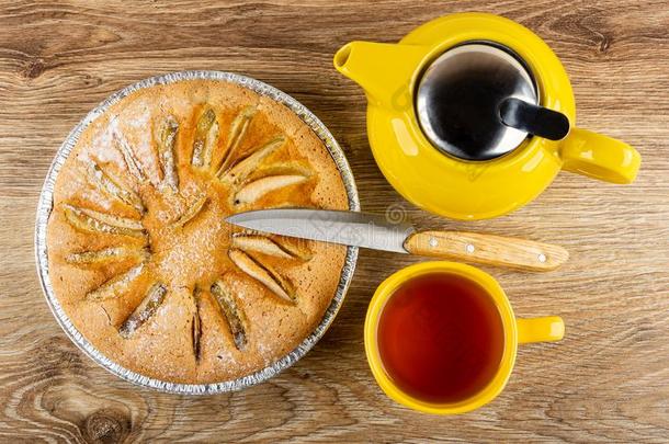 馅饼和苹果水果布丁,刀,黄色的茶壶,杯子和茶水向
