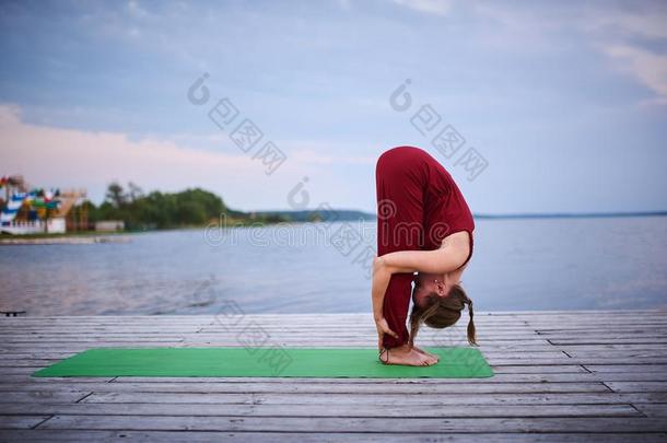 美丽的年幼的女人练习瑜伽瑜珈的任何一种姿势Uttan瑜珈的任何一种姿势-起立