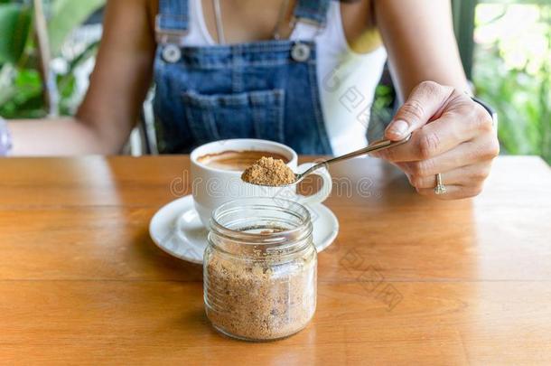 女人手佃户租种的土地勺和棕色的食糖和咖啡豆杯子向tablet药片