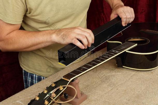吉他修理和服务-工人磨碎黑的吉他颈回纹饰