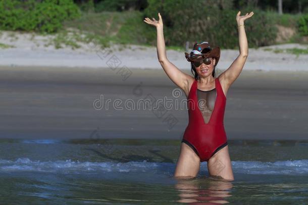 女人和帽子和比基尼式游泳衣<strong>深红色</strong>享有向海滩