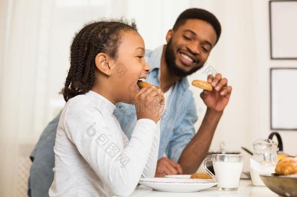 父亲和女儿吃甜饼干,喝饮料奶