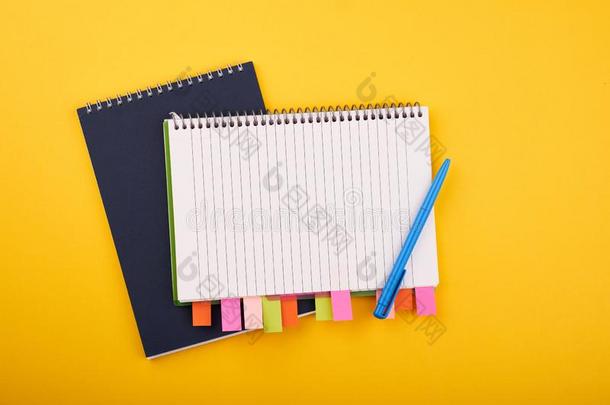 便条簿和颜色有背胶的标签和蓝色笔向黄色的背景