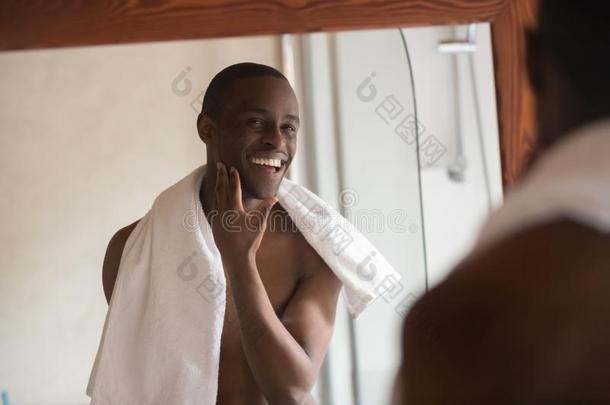 剃过的英俊的非洲的男人有样子的采用镜子摸索满意的