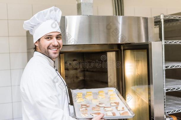 微笑的面包师采用白色的厨师长制服putt采用gbak采用g盘子和家伙