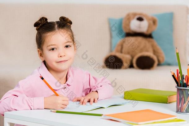 漂亮的小孩文字和铅笔和微笑的在照相机在期间学习